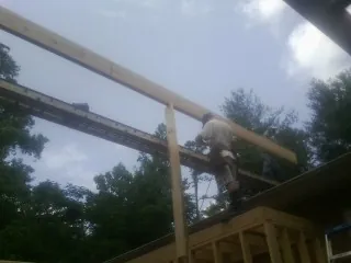 Carpenter setting a ridge beam over a new addition frame — Ice Dam Removal by Roofing Brothers in Loxley