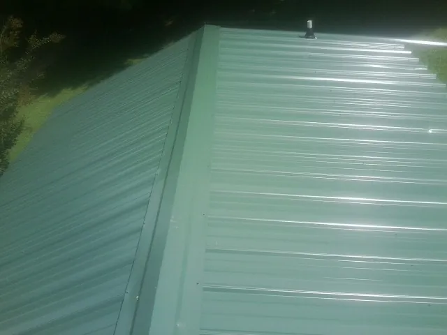 New green metal panels meeting at the ridge of a roof — Flat Roof Repair work by our crew in Loxley