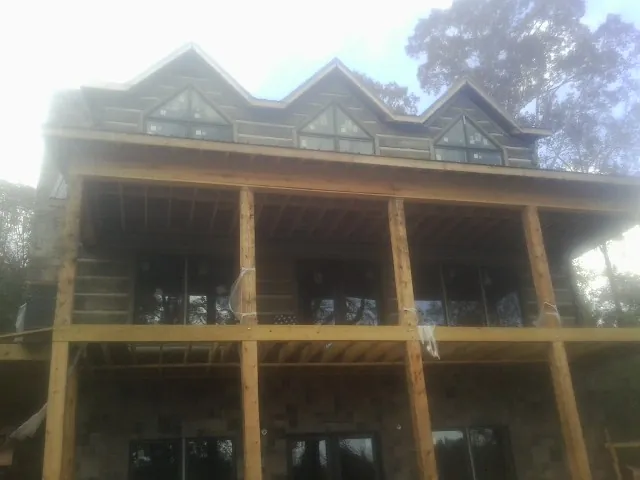 Dormers and porch framing on a large log home under construction — Roof Coating work by our crew in Loxley