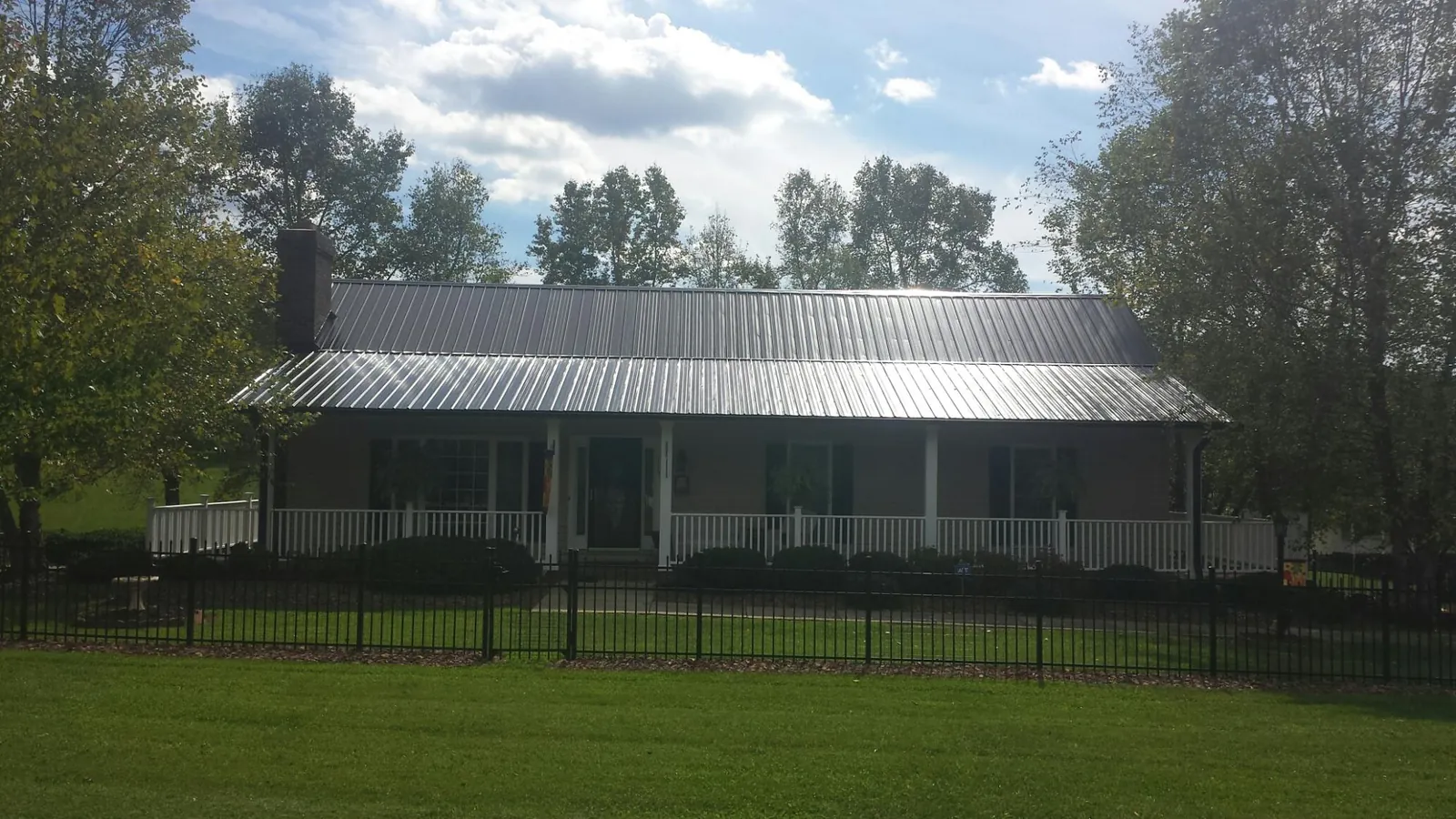Gray metal roof on a brick ranch with a full width front porch — Gutter Guard Installation work by our crew in Loxley