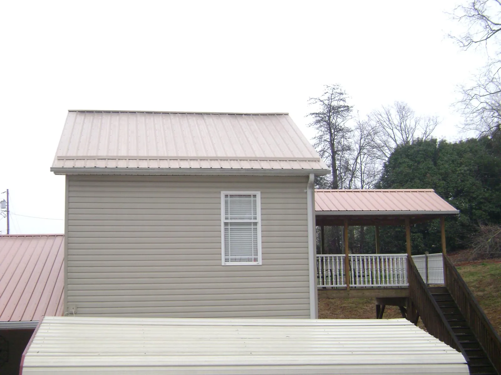 Tan metal roofs on a two story addition and attached porch, from a Roof Replacement job in Loxley
