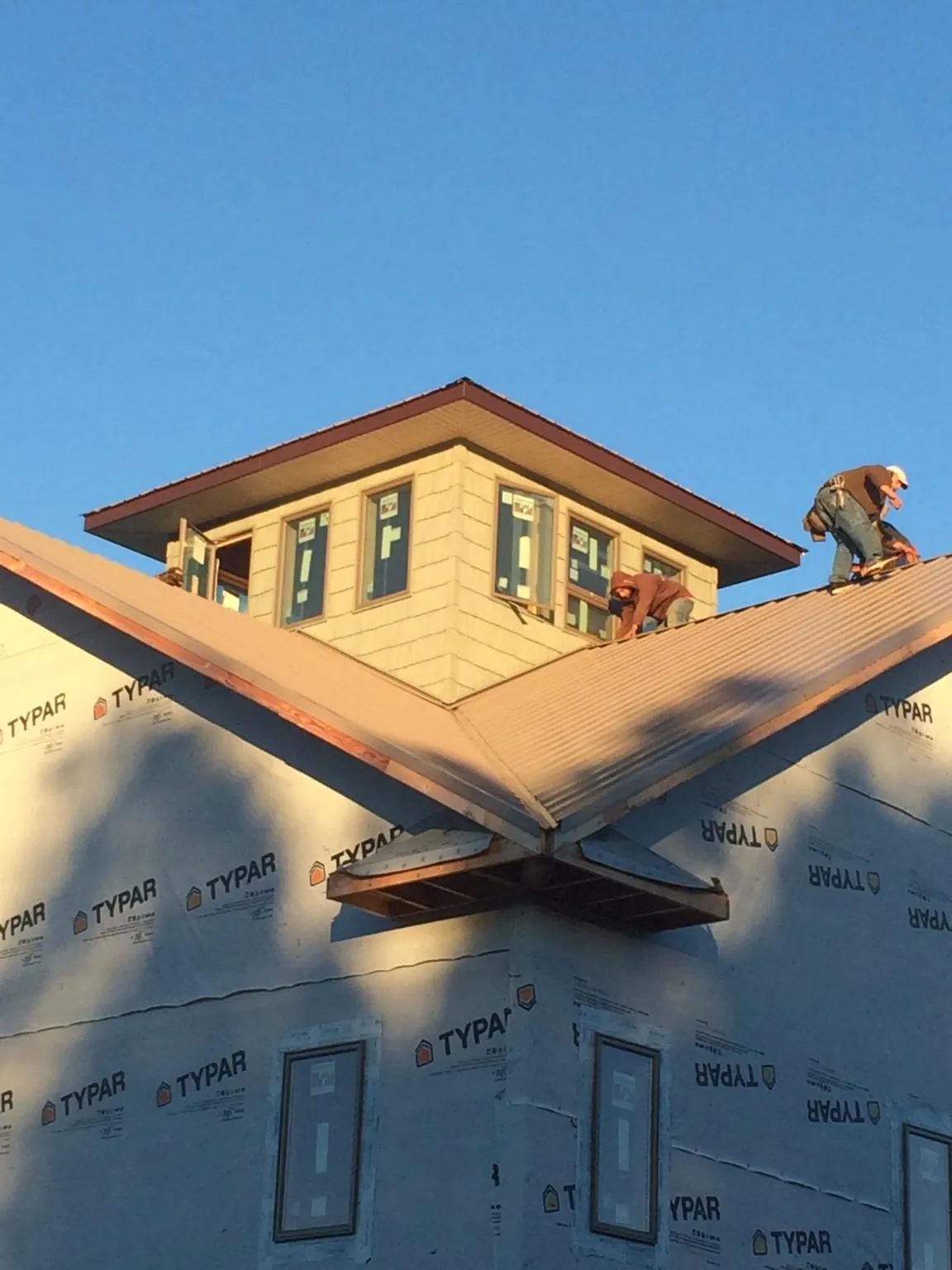 Roofers working around a rooftop cupola on a new metal roof at sunset — Roof Waterproofing in Loxley by Roofing Brothers